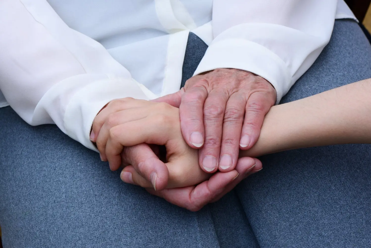 Pflegeteam mit Hand und Herz, Menschen halten sich zum Trost an den Händen